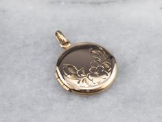 This vintage locket features beautiful floral engravings and has space for two photos, one on the inside of each cover. There is space on the back where a monogram or name can be engraved. Market Square Jewelers works with one of the finest hand engravers in the northeast. With over 30 years of experience, our engraver hand carves lettering, monograms, crests, or patterns in period-specific styles. Choose from our many monogram options shown in the listing or contact us directly with your own cr Luxury Engraved Locket Necklace For Keepsake, Luxury Engraved Round Locket Necklace, Luxury Round Engraved Locket Necklace, Luxury Engraved Locket Necklace For Formal Events, Luxury Engraved Locket Necklace For Formal Occasions, Compact Engraved Jewelry For Wedding, Antique Engraved Locket Necklace With Flower Pendant, Antique Engraved Flower Pendant Locket Necklace, Engraved Flower Pendant Locket Necklace For Wedding