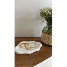 two gold wedding rings sitting on a plate next to a vase with baby's breath flowers