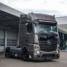 a mercedes semi truck parked in front of a building