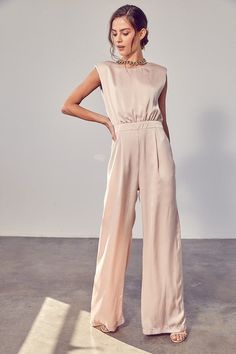 The High Profile Satin Jumpsuit has arrived! Featuring a super comfy satin fabric and loose fit, pockets, a zippered back and button closure, and wide legs, do we need to say more?! Single? This jumpsuit will do all the talking for you. Style with some sandal heels and head to the nearest wine bar stat.  Self: 80% Poly Jumpsuit Outfit Wedding, Tan Jumpsuit, Beige Jumpsuit, Bridesmaids Jumpsuits, Beautiful Jumpsuits, Satin Jumpsuit, Silk Jumpsuit, Outfit Wedding Guest, Two Piece Jumpsuit