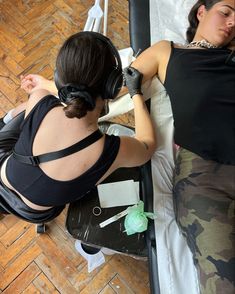 two women laying on top of a bed with headphones in their ears next to each other