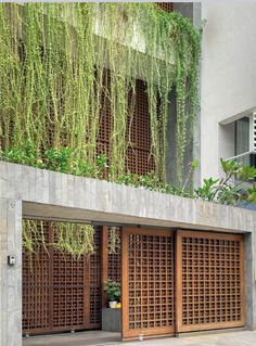 an entrance to a building with plants growing on the wall and wooden doors in front