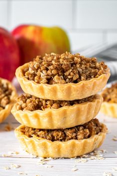 three apple pies stacked on top of each other with apples in the back ground