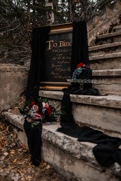 a grave with a sign and flowers on the ground next to some stairs in front of it