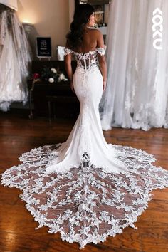 a woman in a white wedding dress standing on a wooden floor with her back to the camera