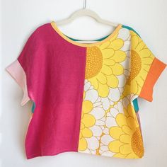 a yellow and pink flowered top hanging on a hanger next to a white wall