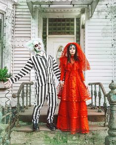 two people dressed up in halloween costumes standing on the front steps of a house with their arms around each other