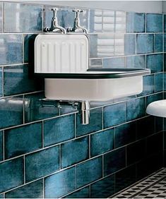 a bathroom with blue tiled walls and black and white flooring, including a pedestal sink