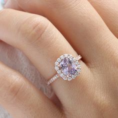 a woman's hand with a pink diamond ring on top of her wedding band