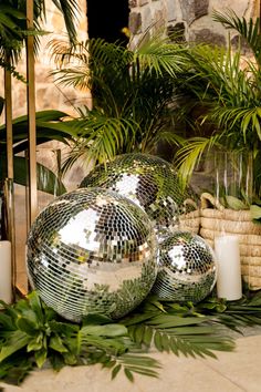 two disco balls sitting next to some plants and candles