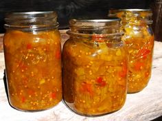 three jars filled with pickles sitting on top of a table