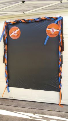 an orange and blue kite hanging from the side of a garage door