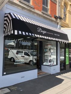 a white van is parked in front of a barbershop with black and white awnings