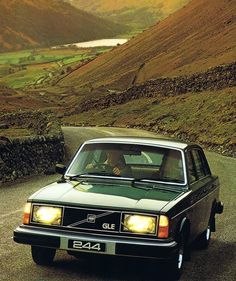 a green car driving down a country road