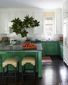 a kitchen with green cabinets and stools in front of the counter top, along with a potted plant on the island