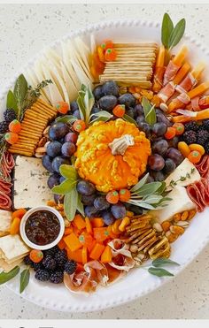 a white platter filled with cheese, crackers, fruit and veggies