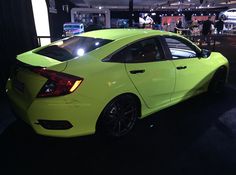 a bright yellow car is on display at an auto show