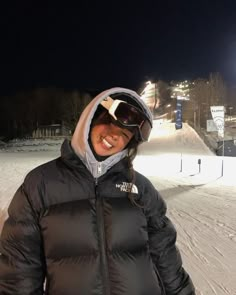 a woman standing on top of a snow covered slope wearing skis and a jacket