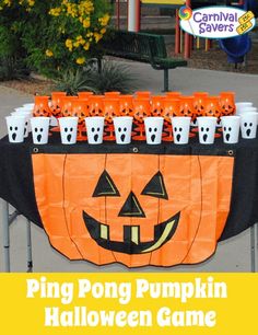 an orange and black table topped with cups filled with halloween drinks, sitting in front of a carnival savers sign