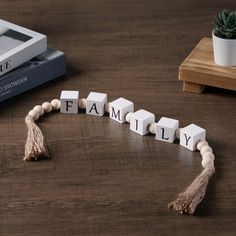 the word family spelled with wooden blocks and tassels on a table next to a plant