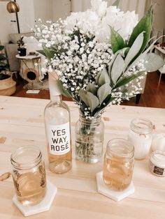 vases filled with flowers sitting on top of a wooden table next to candles and jars