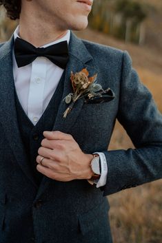 a man in a suit and bow tie is wearing a flower boutonniere