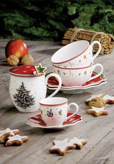 tea cups and saucers decorated with christmas decorations on a wooden table next to cookies