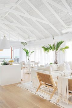 a living room filled with white furniture and lots of plants on top of the couches