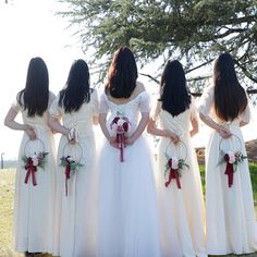 the bridesmaids are wearing white dresses with red ribbons