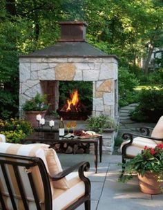 an outdoor patio with chairs, tables and a fire place in the middle of it