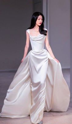 a woman in a white dress is walking down the runway with her hand on her hip