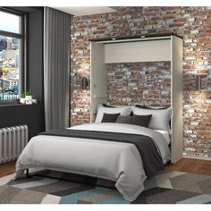 a bedroom with brick walls and a bed in front of a window that has a view of the city