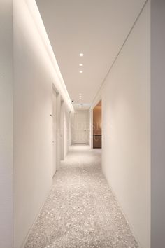 an empty hallway with white walls and carpeting on the floor is lit by recessed lights