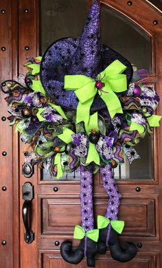 a purple and green wreath on the front door with black booties hanging from it