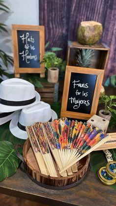 a table topped with lots of hats and cards on top of a wooden table next to plants