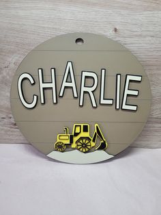 a sign that says charlie with a construction truck in the back and name on it