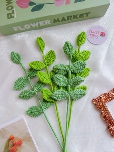 crocheted flowers are on the table next to a flower market box