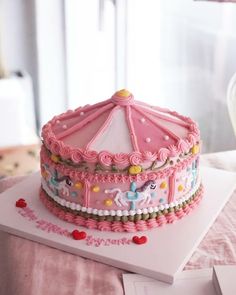 a birthday cake with pink frosting and an umbrella decoration on the top is sitting on a table