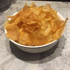 a white bowl filled with potato chips on top of a table