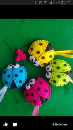 three felt ladybugs are sitting on a green surface