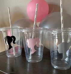 three plastic cups with straws in the shape of animals on them and balloons behind them