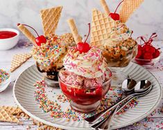 three ice cream sundaes with sprinkles and cherries on a plate