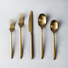 four forks, two spoons and one knife on a white surface