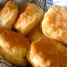 some biscuits are sitting in a basket on a tablecloth with a blue and white checkered cloth