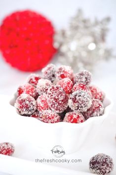 a white bowl filled with powdered sugar covered cranberries next to a silver ornament