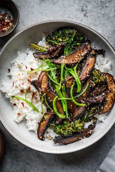 a bowl filled with rice, broccoli and mushrooms on top of a table