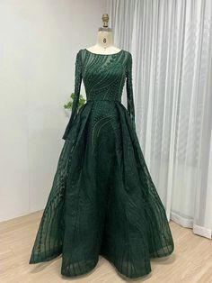 a green dress with long sleeves on a mannequin stand in front of curtains