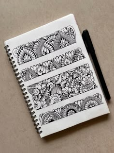 a notebook with some doodles on top of it and a pen next to it