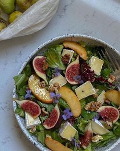 a salad with figs, cheese and nuts in a bowl on a marble table