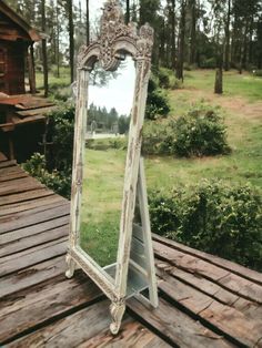 an old mirror sitting on top of a wooden table next to a forest filled with trees